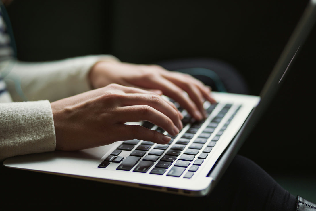 women's hands typing on a laptop keyboard
