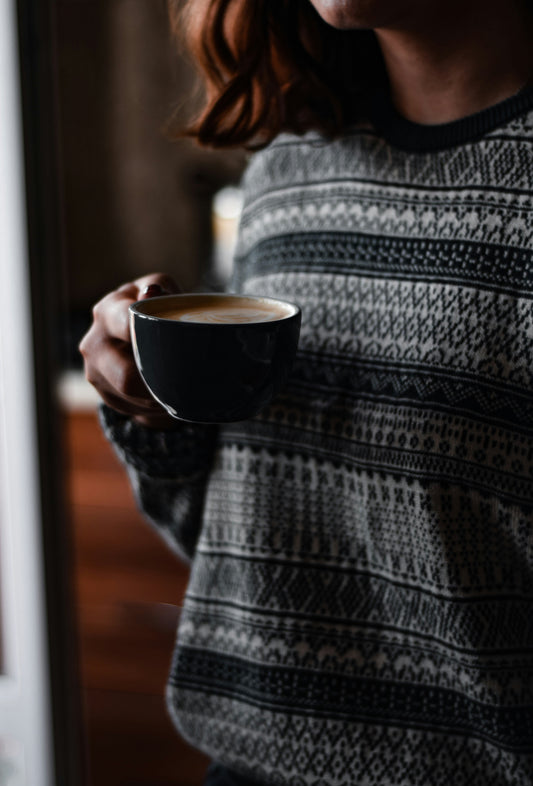 woman in patterned sweater holding a cup of coffee
